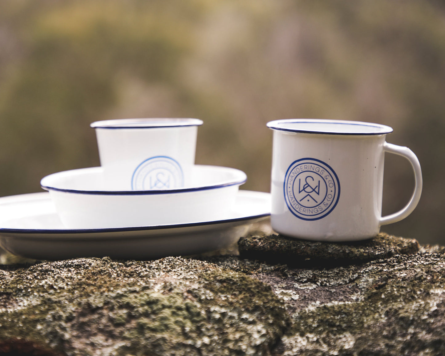 Set of white enamelware with blue accents on a natural stone surface
